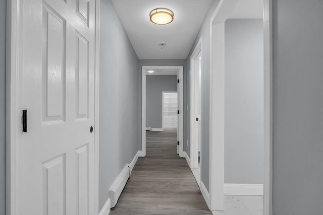 corridor featuring a baseboard heating unit and light hardwood / wood-style floors