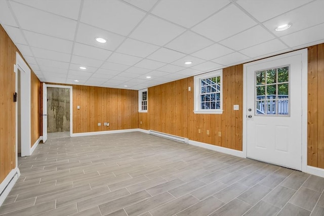 basement featuring a baseboard heating unit and wooden walls