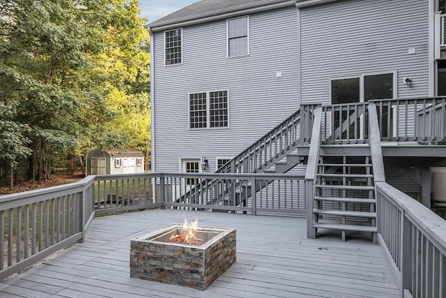 deck with a storage shed and a fire pit