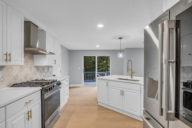 kitchen featuring white cabinetry, wall chimney range hood, sink, and appliances with stainless steel finishes