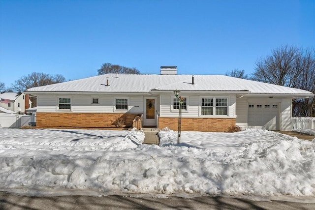 single story home with a garage, a chimney, fence, and brick siding