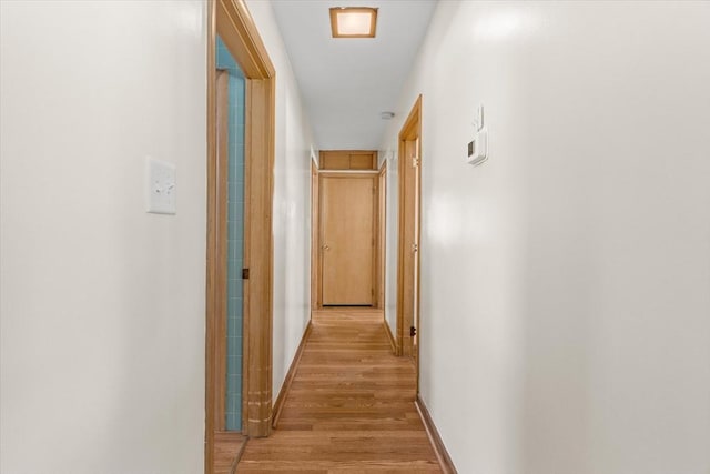 hallway with light wood-style flooring and baseboards