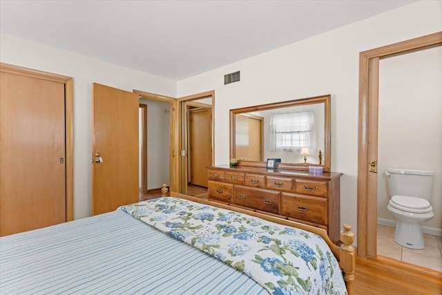 bedroom featuring a closet, light tile patterned flooring, visible vents, and baseboards