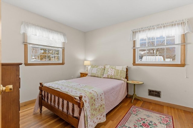 bedroom featuring baseboards, visible vents, and wood finished floors