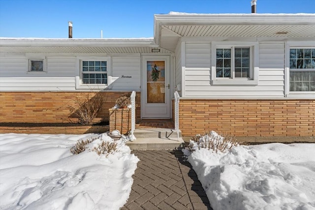 snow covered property entrance with brick siding