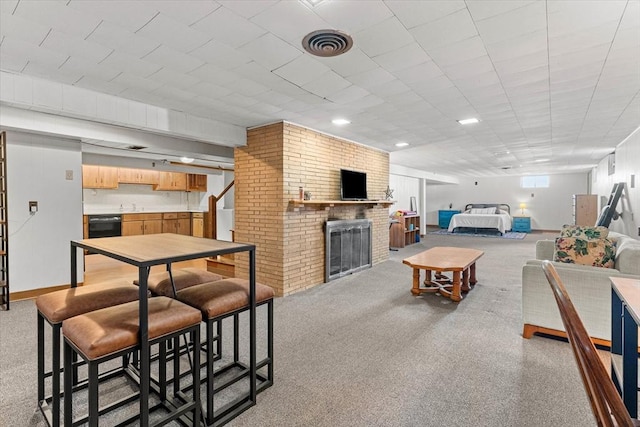 living area with light carpet, a brick fireplace, stairs, and visible vents