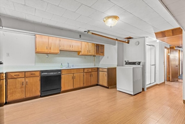 kitchen with black dishwasher, light countertops, washer / clothes dryer, and light wood-style flooring