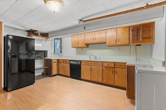 kitchen featuring washer / dryer, light countertops, a sink, and black appliances