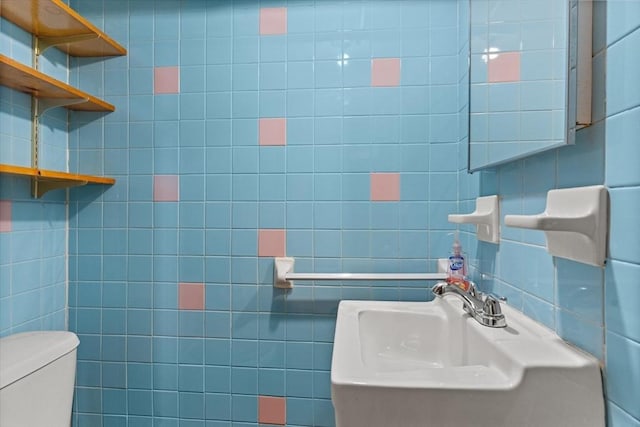 bathroom featuring a sink, toilet, and tile walls