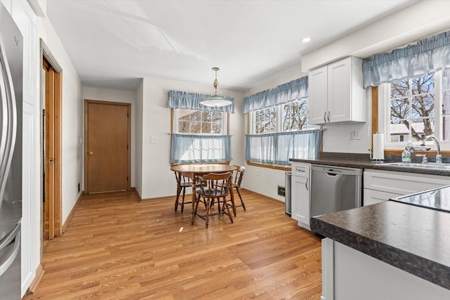 kitchen with stainless steel dishwasher, dark countertops, and white cabinets