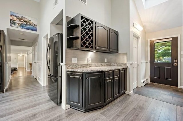 kitchen featuring backsplash, black refrigerator, light hardwood / wood-style floors, and baseboard heating