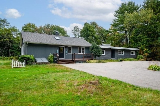 single story home featuring a wooden deck and a front yard