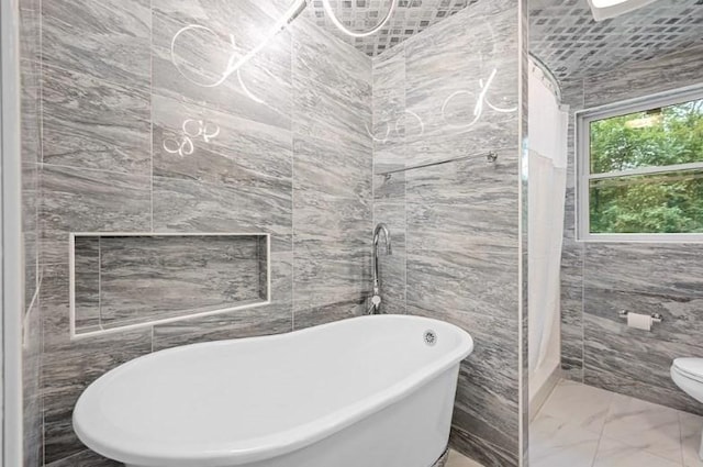 bathroom featuring separate shower and tub, toilet, and tile walls