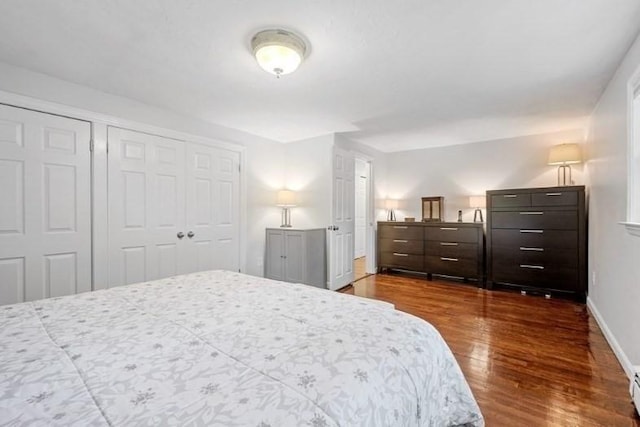 bedroom with dark wood-type flooring and a baseboard heating unit