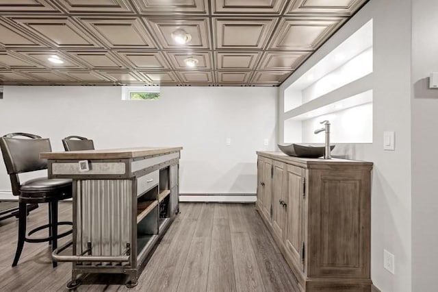 bar featuring light hardwood / wood-style floors, sink, and baseboard heating