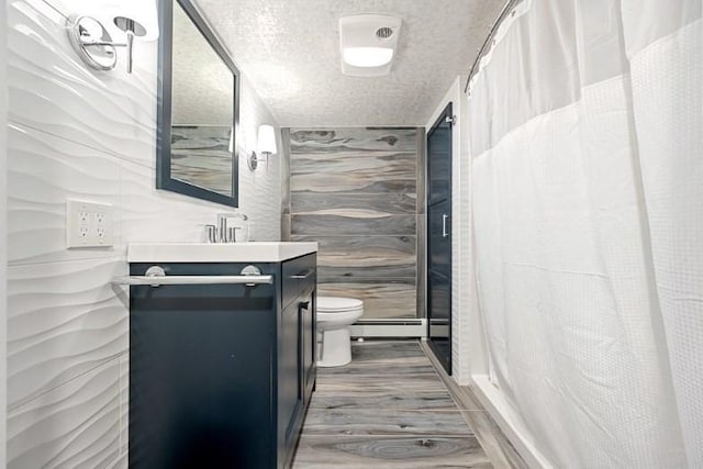 bathroom featuring vanity, a textured ceiling, a baseboard heating unit, hardwood / wood-style flooring, and toilet