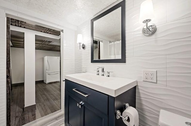 bathroom with a shower with shower curtain, vanity, wood-type flooring, and a textured ceiling