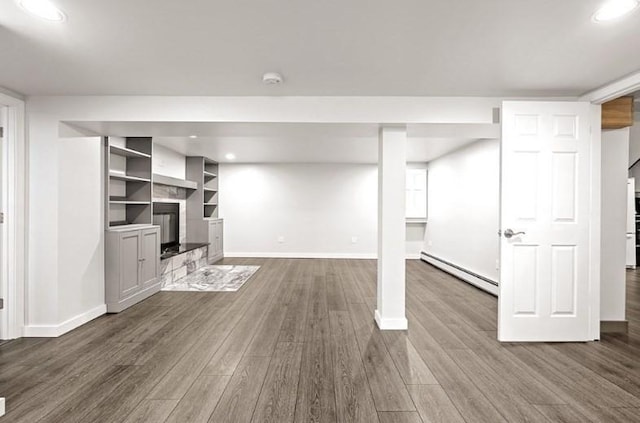 basement featuring dark hardwood / wood-style flooring and a baseboard heating unit