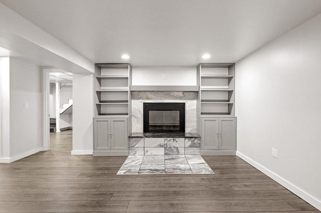 unfurnished living room with dark hardwood / wood-style flooring and a tiled fireplace