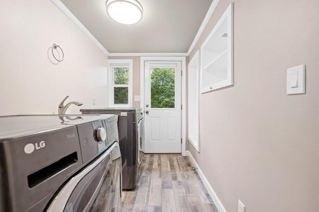 laundry room with crown molding, washer and clothes dryer, and light hardwood / wood-style flooring