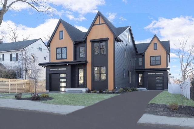 view of front of home featuring a front yard, fence, driveway, and an attached garage