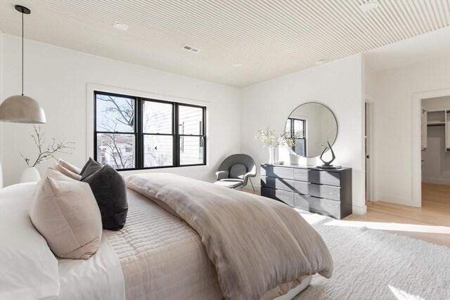 bedroom featuring wood finished floors, visible vents, and baseboards