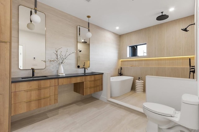 bathroom featuring double vanity, a freestanding bath, toilet, and a sink