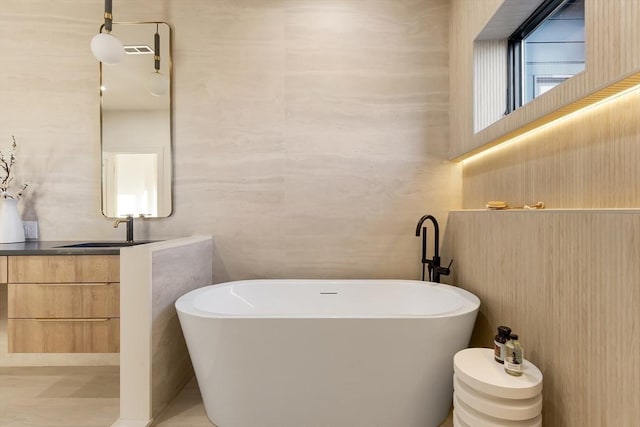 bathroom with a soaking tub, tile walls, and vanity