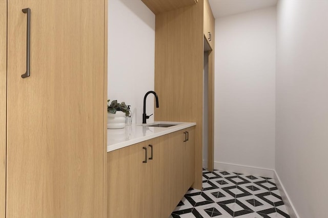 laundry area with light floors, a sink, and baseboards