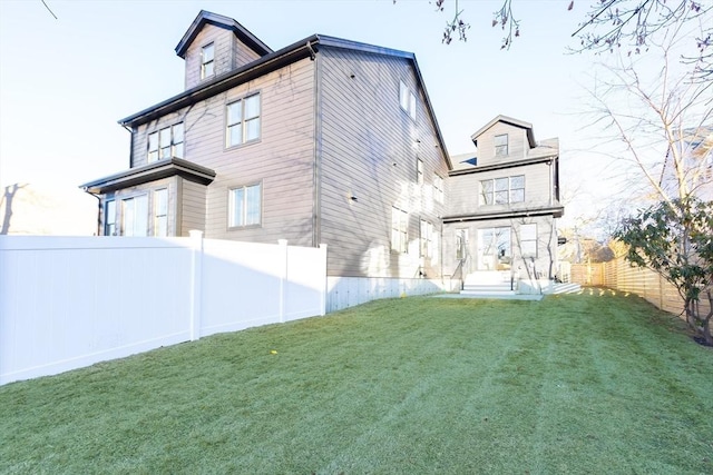 back of property featuring a lawn and fence