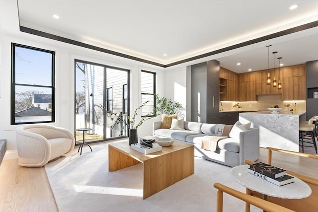 living room featuring light wood-style flooring, a tray ceiling, and recessed lighting