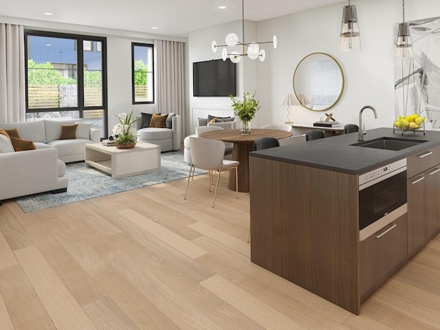 kitchen with pendant lighting, an inviting chandelier, a kitchen island with sink, dark brown cabinets, and sink