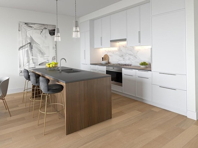 kitchen with sink, oven, white cabinets, and hanging light fixtures