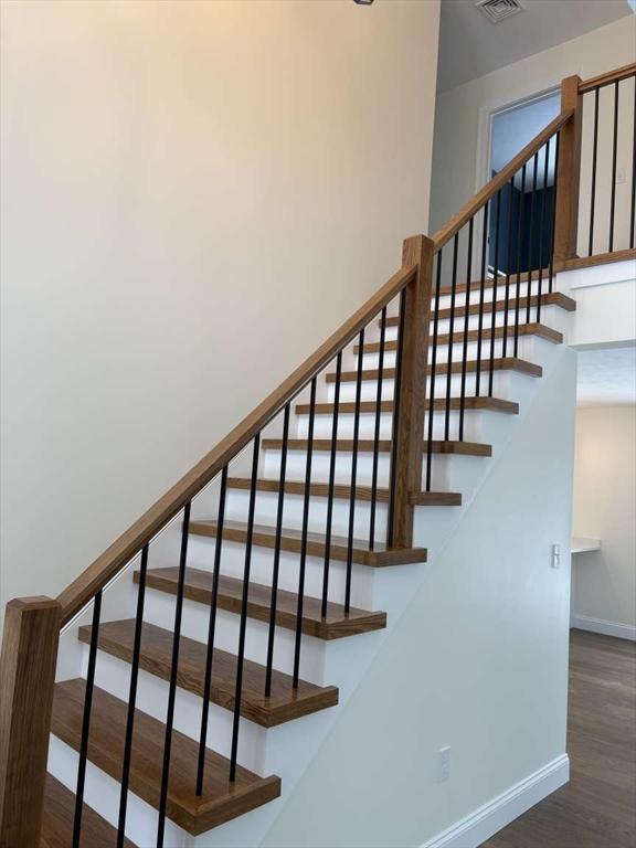 stairway featuring wood finished floors, visible vents, and baseboards