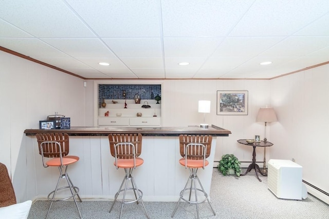 bar with ornamental molding, baseboard heating, a paneled ceiling, and carpet flooring