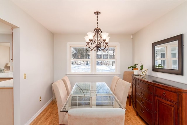 dining space with light hardwood / wood-style flooring and an inviting chandelier