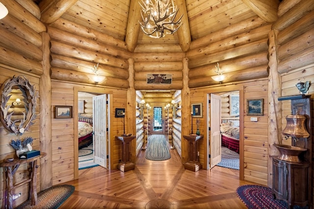 interior space featuring log walls, light hardwood / wood-style floors, wood ceiling, and a chandelier