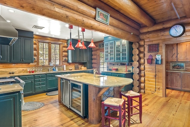 kitchen with log walls, beverage cooler, light stone countertops, and light wood-type flooring