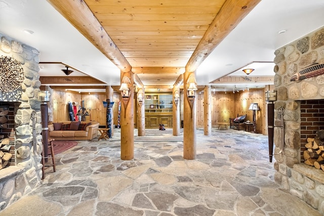 interior space with wood walls, wooden ceiling, and a stone fireplace