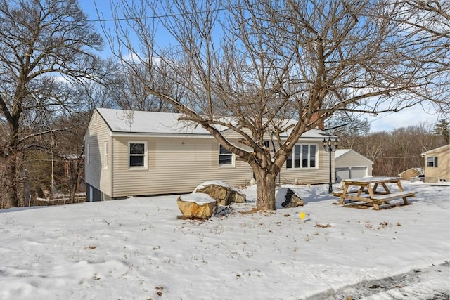 snow covered property featuring a garage and an outbuilding