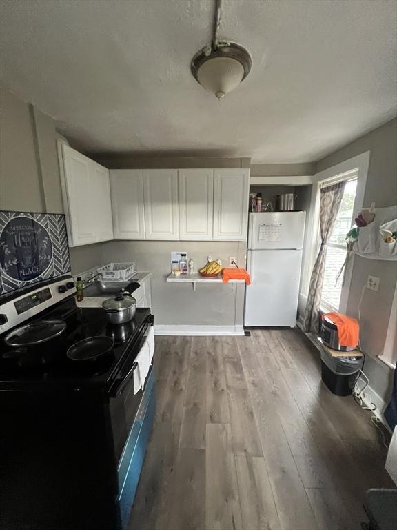 kitchen featuring electric stove, white cabinetry, light hardwood / wood-style floors, and white fridge