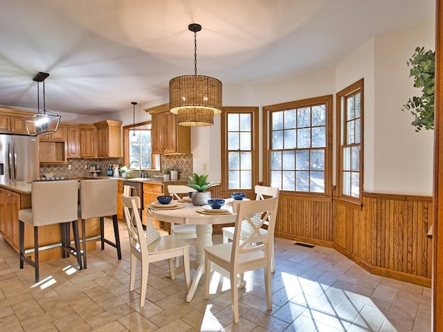 dining space featuring a chandelier, sink, and wood walls