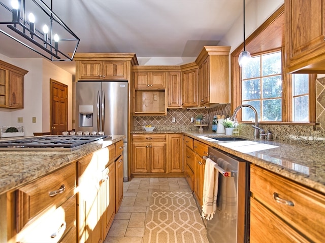 kitchen with sink, stainless steel appliances, light stone counters, decorative light fixtures, and decorative backsplash