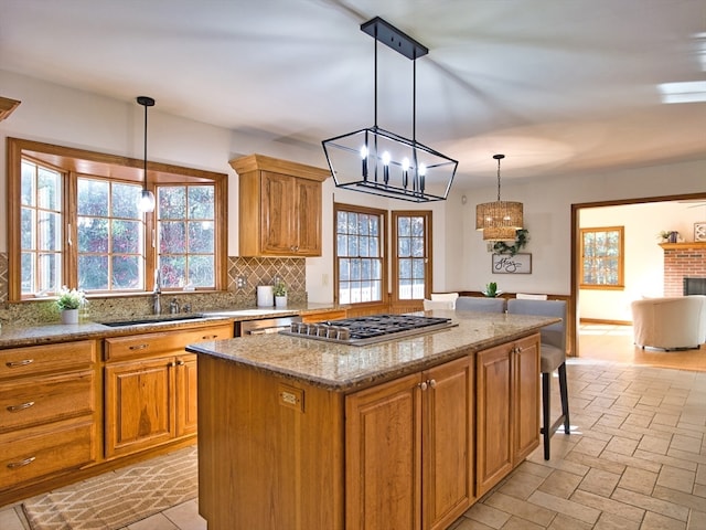 kitchen featuring tasteful backsplash, stainless steel appliances, sink, decorative light fixtures, and a center island