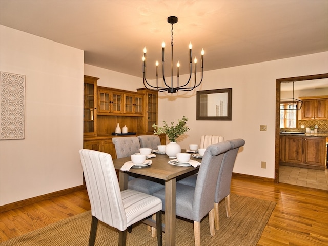 dining space with light hardwood / wood-style flooring and an inviting chandelier