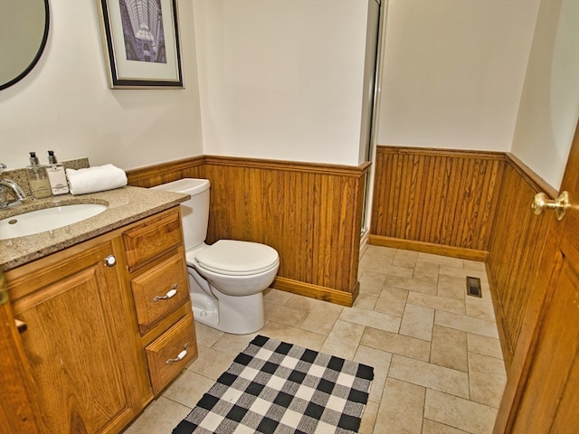 bathroom with vanity, toilet, and wooden walls