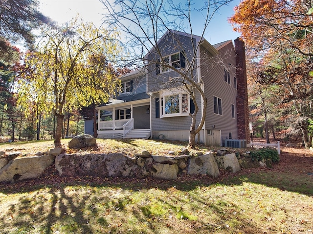 view of front facade with cooling unit, a porch, and a front lawn