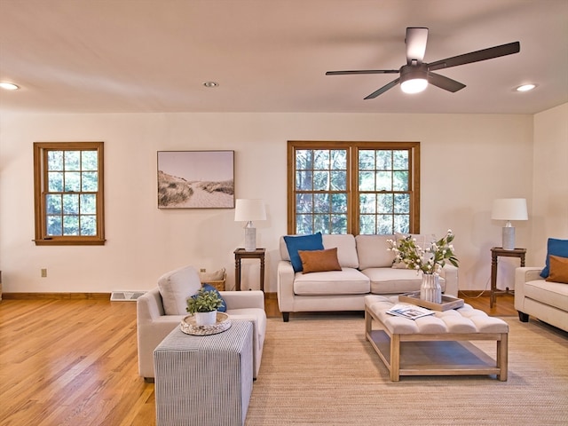 living room with light hardwood / wood-style flooring, ceiling fan, and a healthy amount of sunlight