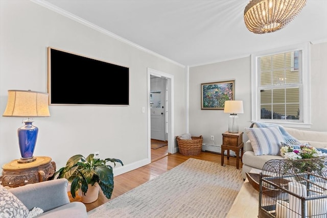 living area with baseboards, a notable chandelier, wood finished floors, and crown molding