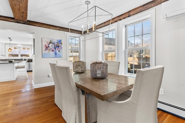 dining space featuring baseboard heating, a wall unit AC, light wood-style flooring, and a healthy amount of sunlight